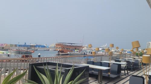 a row of tables and chairs on a deck with a marina at Dar Shaden hostel in Muscat