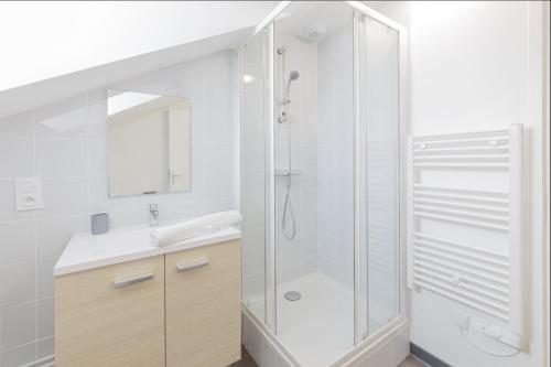 une salle de bain blanche avec une douche et un lavabo dans l'établissement LE MONKEY 700m Gare Wi-Fi, à Laval