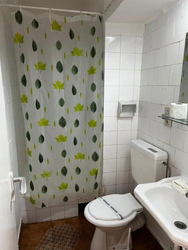 ein Badezimmer mit Toilette und Duschvorhang mit Blättern in der Unterkunft Hotel National in Mamaia