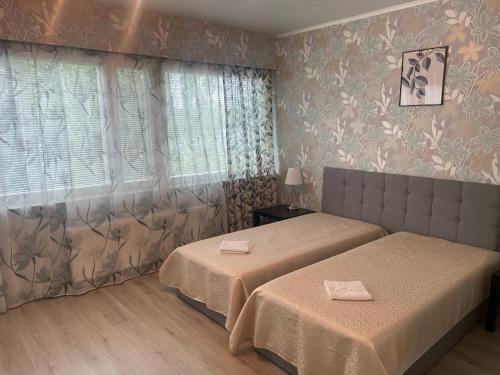 a hotel room with two beds and a window at Hotel Ilomantsi North Star in Ilomantsi