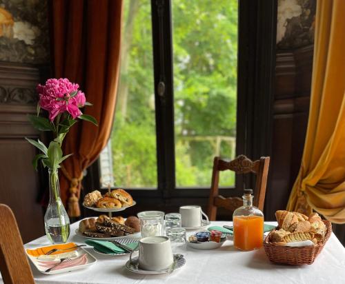 ein Tisch mit Frühstücksspeisen und eine Vase mit rosa Blumen in der Unterkunft Relais des Anges in Abbeville