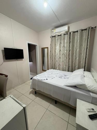 a bedroom with a bed and a television in it at Hotel Ferrari in Rio do Sul