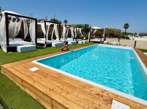 une grande piscine avec une terrasse en bois dans l'établissement Hotel La Pergola, à Alba Adriatica