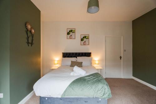 a bedroom with a bed with white sheets and green walls at The Alfred Suite in Redcar
