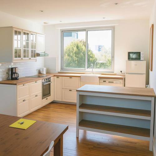 une cuisine avec des placards blancs et une grande fenêtre dans l'établissement Duplex lumineux 4 chambres et 2 SDB proche gare, à Angers