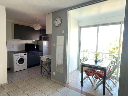 une cuisine avec une table et une horloge au mur dans l'établissement Charmant 2 pièces cabine moderne, parking inclus, proche plage et commerces, animaux admis - FR-1-307-8, au Grau-du-Roi