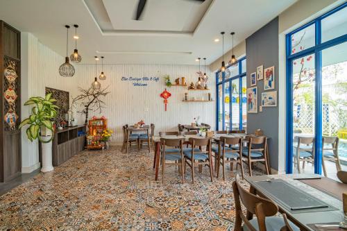 ein Esszimmer mit Tischen, Stühlen und Fenstern in der Unterkunft Blue Boutique Villa Hoi An in An Bàn (2)