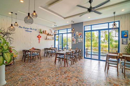 ein Esszimmer mit Tischen, Stühlen und Fenstern in der Unterkunft Blue Boutique Villa Hoi An in An Bàn (2)