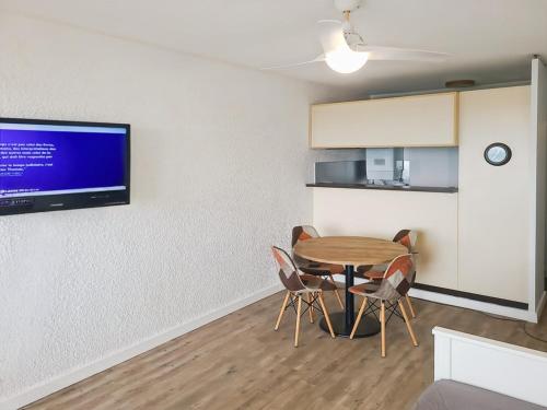 Cette chambre dispose d'une table, de chaises et d'une télévision murale. dans l'établissement Studio cabine avec terrasse et parking à Palavas - FR-1-559-43, à Palavas-les-Flots