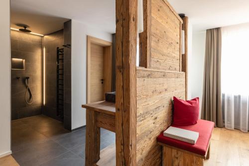 Habitación con pared de madera y silla roja. en Das Denisl, en Reit im Winkl