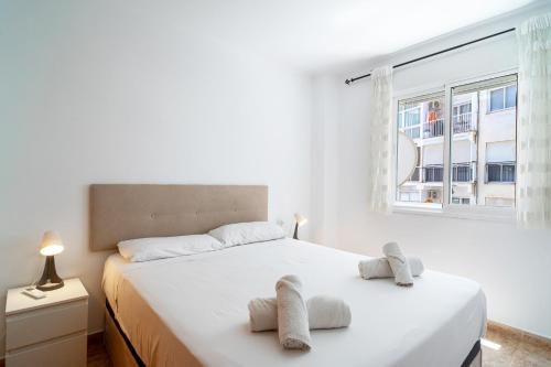 biała sypialnia z dużym łóżkiem i ręcznikami na nim w obiekcie Apartmento Caribe Centro Casasol w mieście Nerja