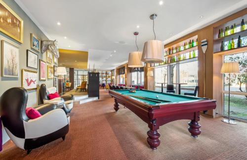 a billiard room with a pool table and chairs at Leonardo Hotel Hannover Medical Park in Hannover