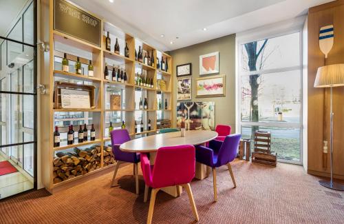 a dining room with a table and purple chairs at Leonardo Hotel Hannover Medical Park in Hannover