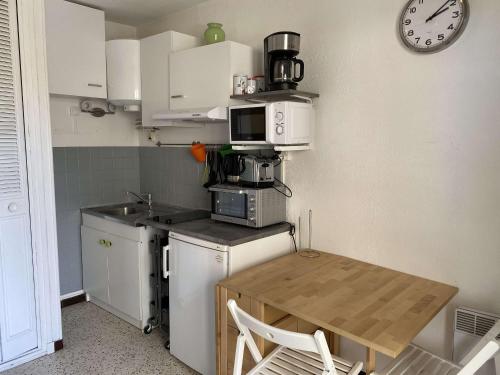 une petite cuisine avec une table et une horloge murale dans l'établissement Studio climatisé avec balcon proche centre et thermes, Balaruc-les-Bains - FR-1-553-21, à Balaruc-les-Bains