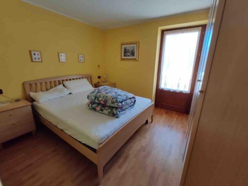 a bedroom with a bed and a window and a door at Da Nadia a Ossana casetta in Val di Sole in Ossana