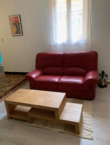 ein rotes Sofa in einem Wohnzimmer mit einem Couchtisch in der Unterkunft Carcassonne Studio in Carcassonne