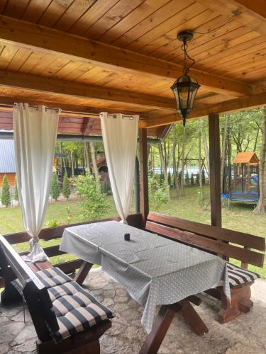a table and a bench under a wooden roof at Holiday Home UnaPark in Krakovo
