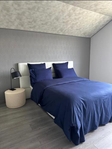 a bedroom with a bed with blue sheets and a ceiling at La Maison du Rond-Buisson in Maîche