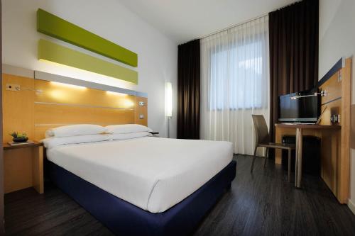 a hotel room with a large bed and a television at iH Hotels Milano Gioia in Milan