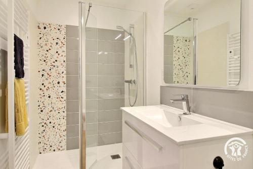 une salle de bain blanche avec un lavabo et une douche dans l'établissement La maison d'anne-claire, à Ploemeur