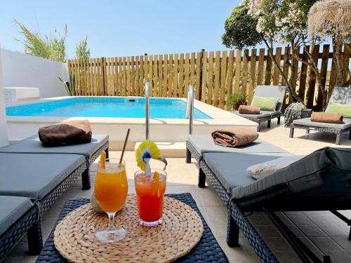 two drinks on a table in front of a pool at Dune Pearl Villa - Private Spa - Duna Parque Group in Vila Nova de Milfontes