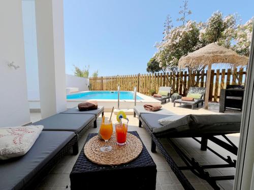 a patio with two drinks on a table next to a pool at Dune Pearl Villa - Private Spa - Duna Parque Group in Vila Nova de Milfontes