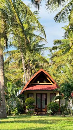 a house with palm trees in front of it at Pondok Siola in Labuhan Pandan