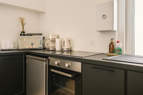 une cuisine avec une cuisinière et un comptoir dans l'établissement La Maison d'Alcyone by Melrose, à Bayeux