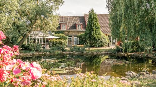 a house with a pond and flowers at Landhaus Alte Schmiede in Niemegk