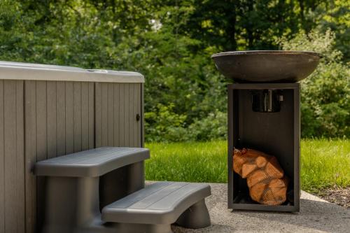 a grill with a bowl on top and a bench at Lodge met Jacuzzi - 4 personen - Woodz Lodges in Heusden - Zolder