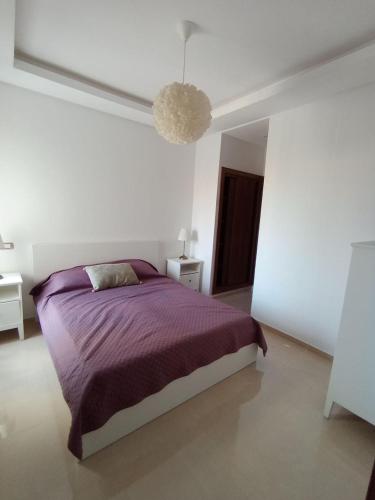 a bedroom with a purple bed in a white room at Charming appartement in Bouznika in Bouznika
