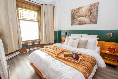 a bedroom with a large bed with a tray on it at Elegant Escape, Modern Luxe in Historic Suite in Saint John