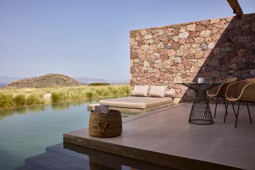 a patio with a couch and chairs next to the water at D3 Milos in Plaka Milou