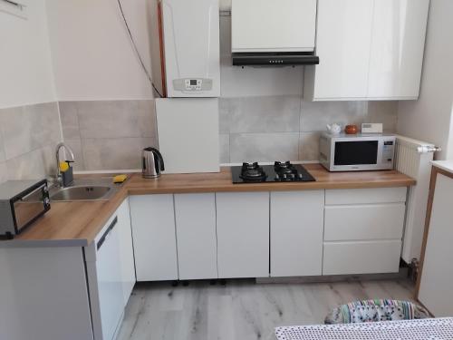 a kitchen with white cabinets and a sink and a microwave at U Józka in Kowary