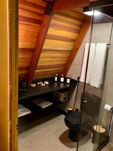 a bathroom with a black toilet and a wooden ceiling at Cabanas do Cerrado Brasil in Novo Gama