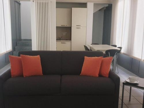 a living room with a black couch with orange pillows at APPARTAMENTO MODERNO con parcheggio gratuito di fronte in Lecco