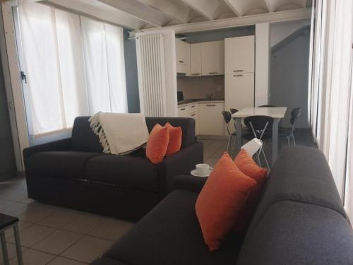 a living room with a black couch with orange pillows at APPARTAMENTO MODERNO con parcheggio gratuito di fronte in Lecco