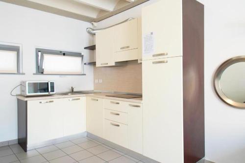 a kitchen with white cabinets and a microwave at APPARTAMENTO MODERNO con parcheggio gratuito di fronte in Lecco