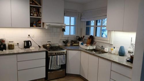 a kitchen with white cabinets and a stove top oven at Casa del Cerrito in Tandil