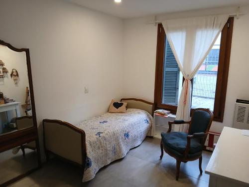 a bedroom with a bed and a window and a chair at Casa del Cerrito in Tandil
