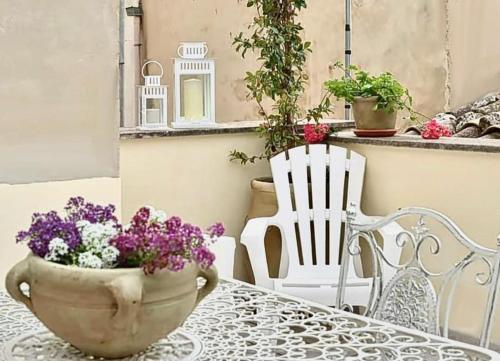 un tavolo con un vaso di fiori e una sedia bianca di Casa Dolce Casa a Modica