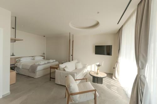 a white bedroom with a bed and a couch at Theros Kourouta Boutique Hotel in Kourouta
