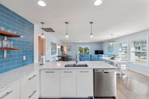 a kitchen and living room with white cabinets and blue tiles at Now Youre Cookin in Duck