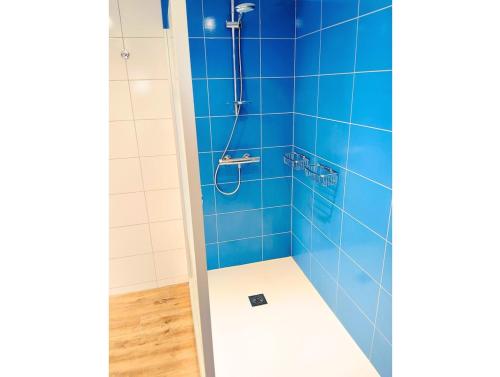a blue tiled shower with a shower head at Gîte de l'Église de la Pommeraie in La Pommeraie-sur-Sèvre