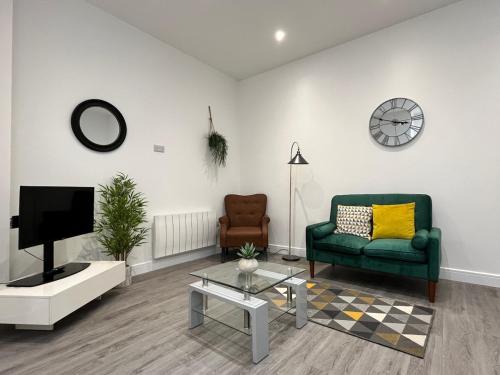 a living room with a green couch and a tv at The Coastal Getaway in Isle of Wight