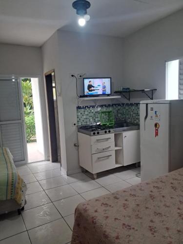 a kitchen with a stove and a tv on the wall at Kitnets & Flats in Ubatuba