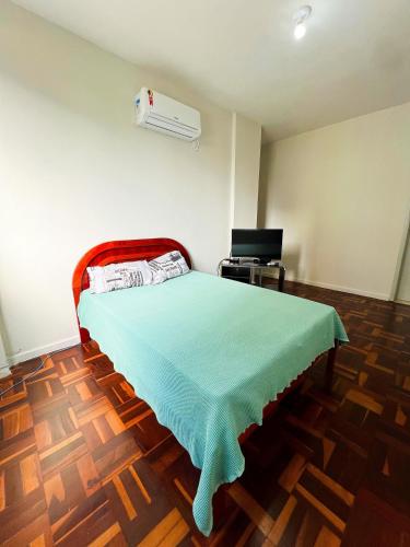 a bedroom with a bed with a green blanket at Amplo apê em bairro nobre in Atalaia Nova
