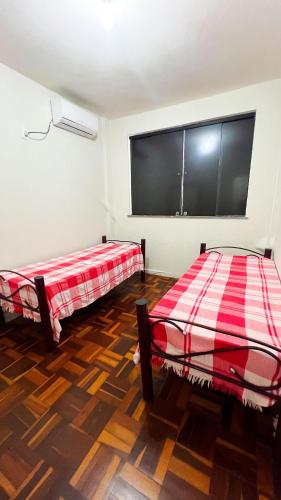 two beds in a room with a large screen at Amplo apê em bairro nobre in Atalaia Nova