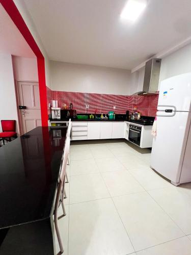 a kitchen with a white refrigerator and red tiles at Amplo apê em bairro nobre in Atalaia Nova