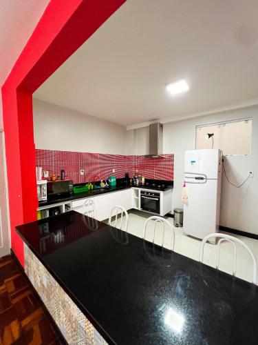 a kitchen with a white refrigerator and a red wall at Amplo apê em bairro nobre in Atalaia Nova